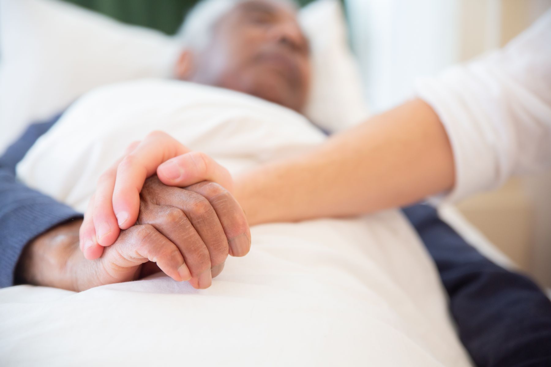 A younger hand gently holding an older person's hand